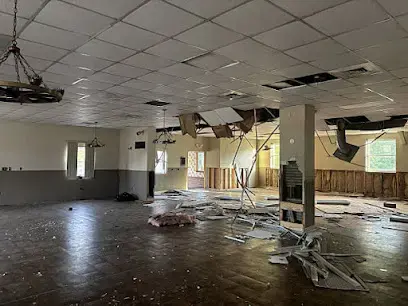 Ceiling tiles fallen across the floor of a large commercial room after a water leak