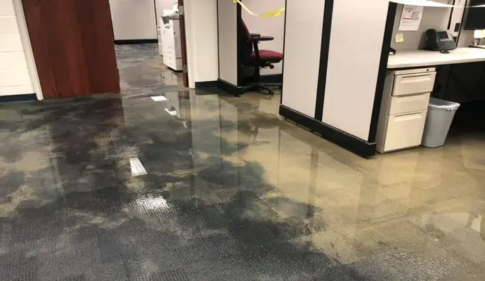 Standing water spread across the floor of an office with cubicles