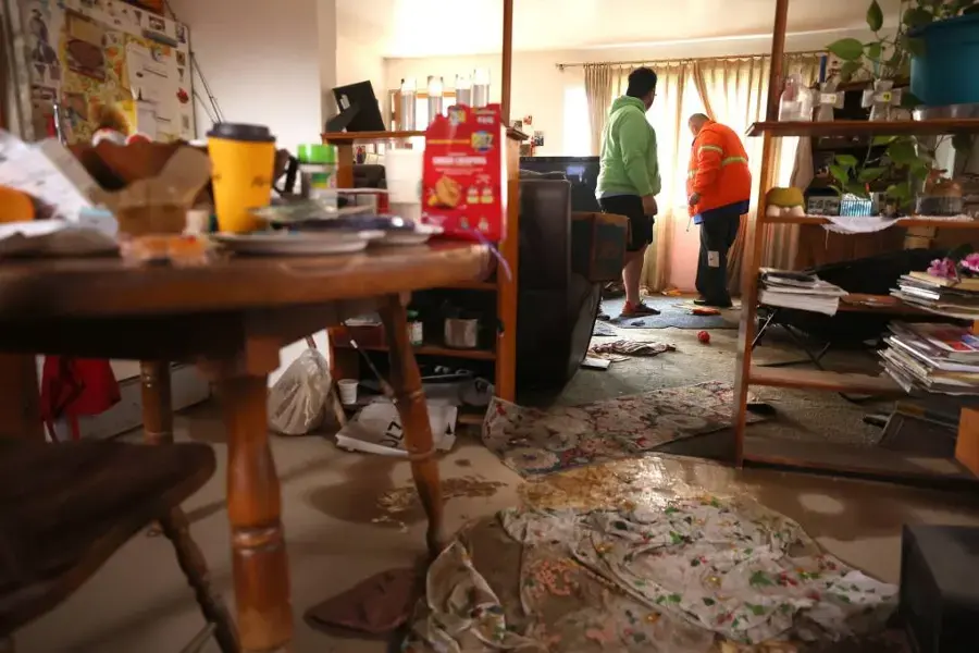 Workers clearing a living room left wet and littered after storm floodwater came in
